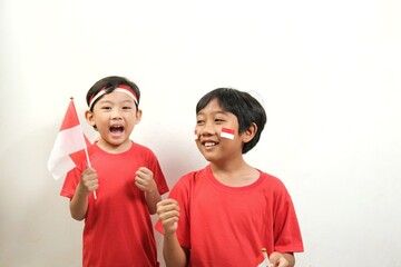 Two boys joyfully celebrate Indonesian Independence Day with flags, face paint, and big smiles....