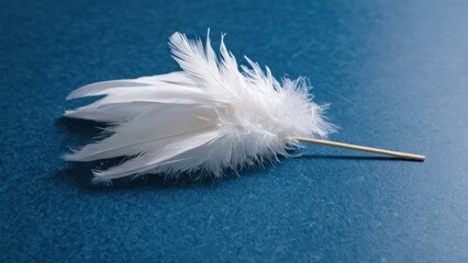 bunch of white feathers laying on top of a blue surface next to a toothpick