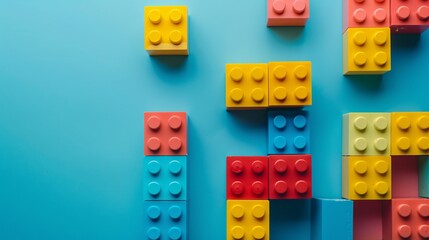 Obraz premium Closeup of colorful plastic building blocks on blue background with copy space.