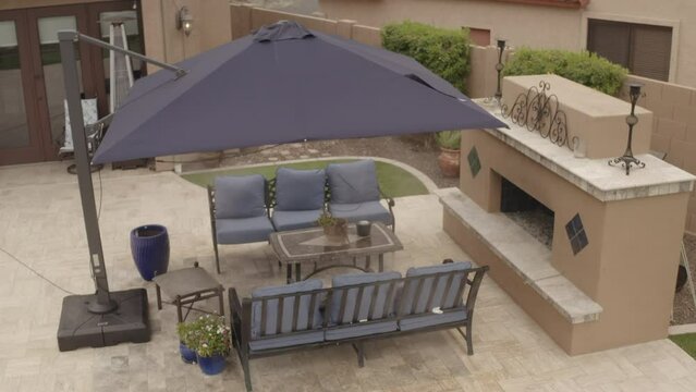 An aerial 4k video of a Deseret landscaped backyard in Arizona featuring a travertine tiled pool deck with a spa, outdoor fireplace, outdoor kitchen and putting green.