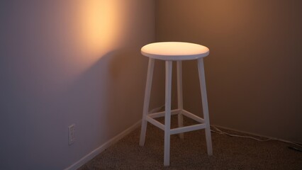 white stool sitting in a room next to a wall with a light coming through it