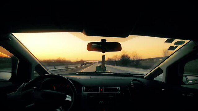 Pov of travel car driving down a road on vacation with a beautiful sunset in the background.