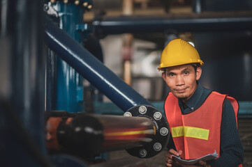 Asian engineer diligently inspects machinery in an industrial factory.Asian workers diligently...