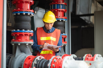 Asian engineer diligently inspects machinery in an industrial factory.Asian workers diligently...
