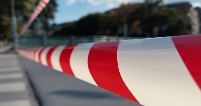 A red and white ribon striped barrier is on the road at traffic accident