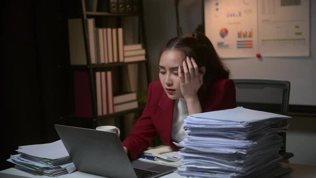Stressed businesswoman working late into the night, feeling overwhelmed and exhausted, eventually falling asleep on a stack of documents in her office