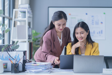 A professional photograph depicting two female entrepreneurs engaged in a collaborative discussion while diligently working in their corporate office environment.