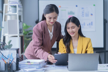 A professional photograph depicting two female entrepreneurs engaged in a collaborative discussion while diligently working in their corporate office environment.