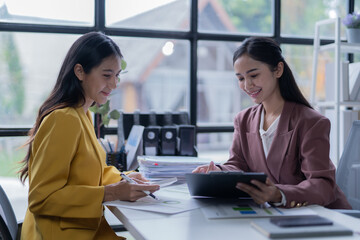A professional photograph depicting two female entrepreneurs engaged in a collaborative discussion while diligently working in their corporate office environment.