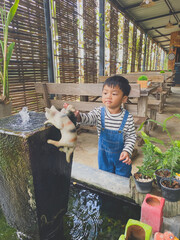 Hispanic child enjoying gardening outdoors with potted plants and watering them in the summer
