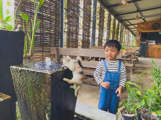 Hispanic child enjoying gardening outdoors with potted plants and watering them in the summer