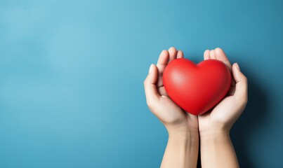 Fototapeta premium Hands Holding a Red Heart on a Blue Background