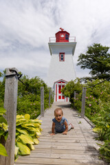 Toddler girl crawling in front of light house 