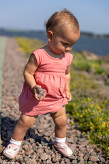 Toddler girl holding rocks on wooden path 
