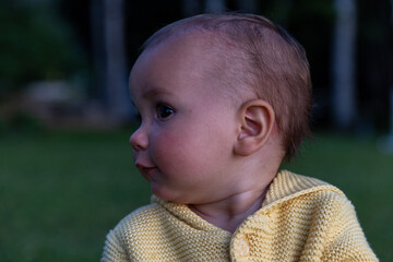 Toddler girl outside at sunset looks away from camera - side profile 