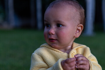Toddler girl outside at sunset looks away camera  