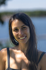 Woman in 20s smiles and looks towards camera 