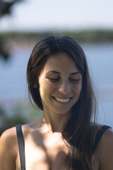 Woman in 20s smiling looking down and away from camera 