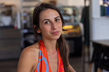 Young woman sitting in resturant looks forward 