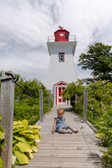 Toddler girl playing in front of lighthouse 