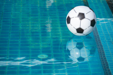 An Inflatable football floating on the surface of swimming pool.