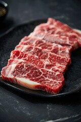 Fototapeta premium A slab of meat with white stripes on it. The meat is on a black plate