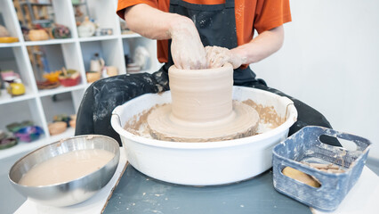 Close-up of a potter's hands working on a pottery wheel. 