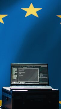 Vertical video Laptop in European Union command center used by counterterrorism department to run security protocols against propaganda bots trying to destabilize democracy, isolated over EU flag