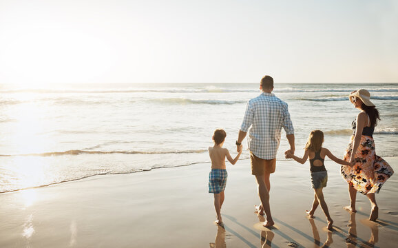 Family, walking and holding hands with children on beach for summer holiday, weekend or bonding together in nature. Back view of mother, father and kids strolling on ocean coast for sunset vacation - Powered by Adobe