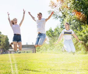 Obraz premium Three joyful teens jump on a spring lawn