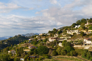 Obraz premium Hillside Village Homes With Lush Greenery and Cloudy Sky in the Afternoon