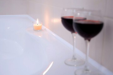 Romantic decoration atmosphere in bathroom with two wine glasses and burning candle. Preparation for date, pleasure evening for couple lovers at home, hotel on weekend. Romantic relationship concept.