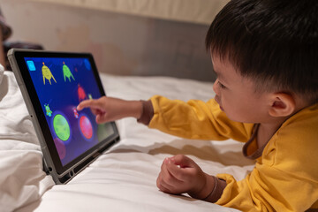 Little boy using portable device to playing game © alenthien