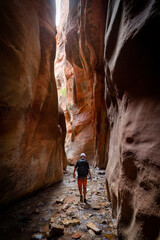 Young man walking through a scenic slot canyon near Zion National Park in Utah. Hiking Adventure in the beautiful Southern Utah region - a great outdoor recreation spot.