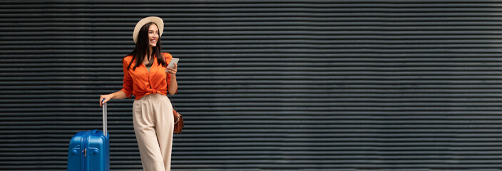 Cheerful Passenger Woman With Travel Suitcase Using Smartphone Texting While Waiting For Transport...