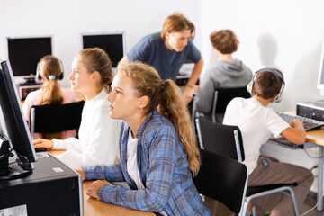 Fototapeta premium Teenager girls and boys studying in computer lab during lesson.