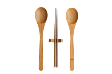 A set of wooden chopsticks and two spoons. The chopsticks are held together by a wooden ring. The spoons are laid out next to the chopsticks.