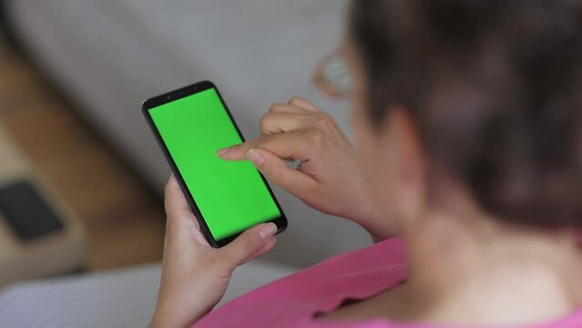 Woman use smart phone with green screen at home