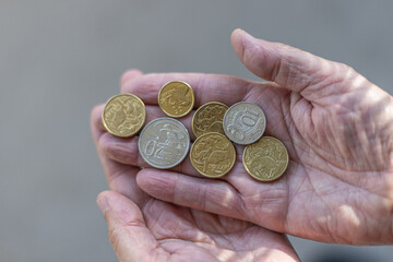 A few Australian dollar coins held on a man's hand, in the sun.