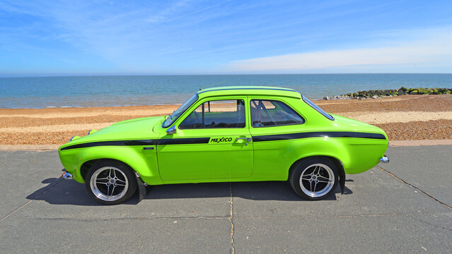 Classic 1972 MK1 Ford Escort Mexico YB Turbo parked on seafront beach and sea in background.