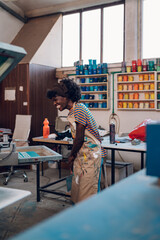 Smiling diverse graphic engineer preparing for silk screen printing.