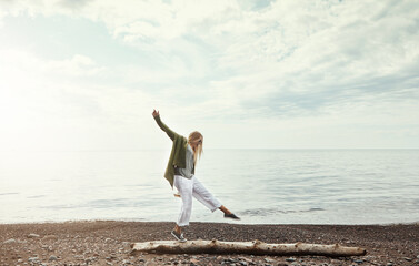 Balance, beach and woman walking on log outdoor in summer for hobby, leisure or vacation. Earth, freedom and sky with person having fun by ocean for break or fresh air, holiday and weekend trip