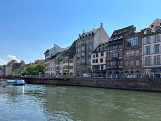 Naklejka premium Sightseeing boat is touring Ill river along Quai Saint-Nicolas in Strasbourg, Grand Est, France, June 2023