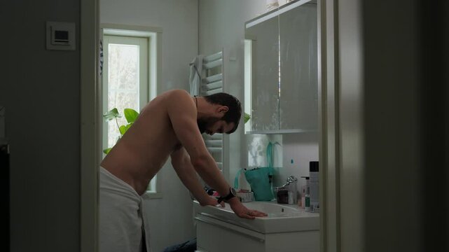 Young man in the bathroom crestfallen with regret shaking head