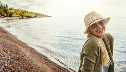 Happy woman, portrait and laughing with glasses at beach for holiday, weekend or outdoor getaway. Young female person with smile in fashion for fun journey, trip or happiness by ocean coast in nature