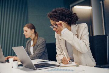 Focused young businesswomen use gadgets while working in coworking. Distance work concept