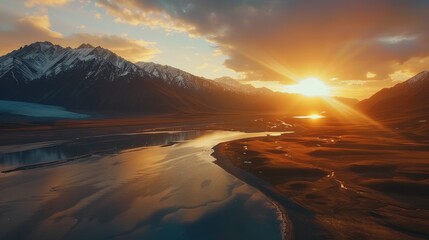 A stunning aerial view of a sunset over a river with towering mountains in the background.