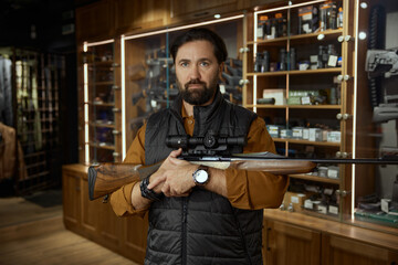 Salesman demonstrating rare collectible hunting rifle over gun shop interior