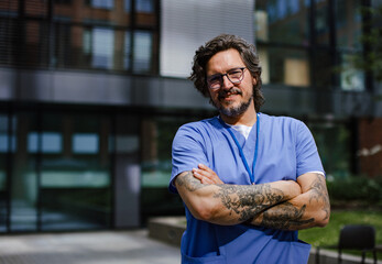 Portrait of handsome doctor in uniform outdoors. Work-life balance of healthcare worker.