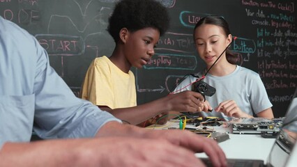 Young student fixing controller while teacher programming engineering code at STEM class. Closeup of instructor hand typing computer while smart girl using electronic tool and blackboard. Edification